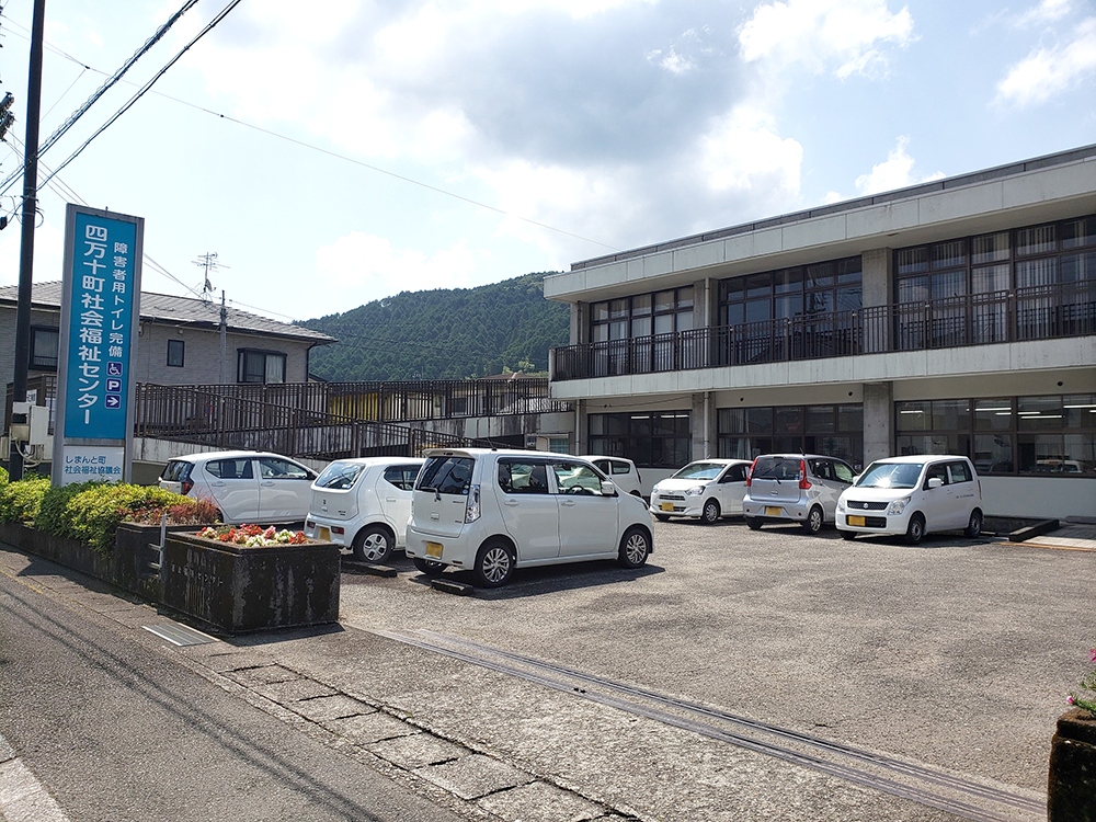 介護施設の駐車場と建物外観。複数の福祉車両が停まっている。
